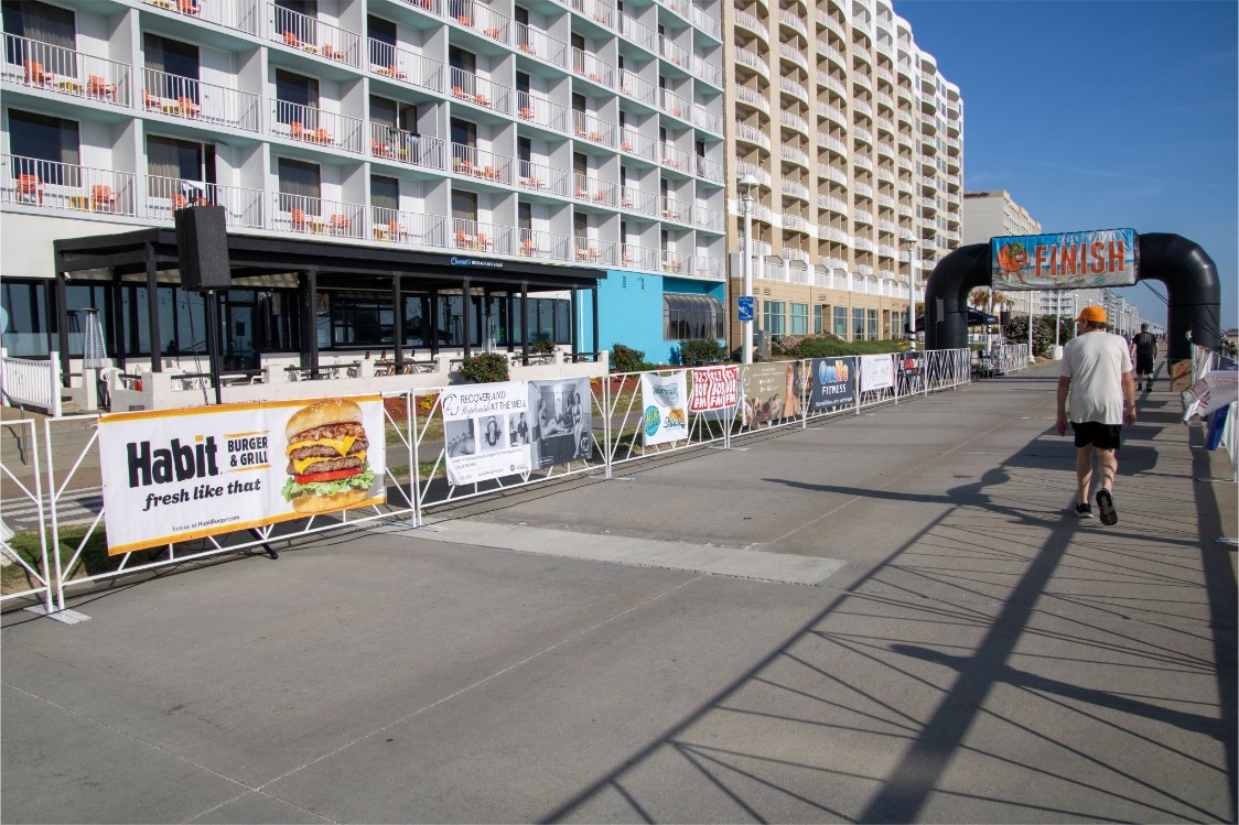 Wide shot of a race course along a beach boardwalk lined with Habit Burger banners